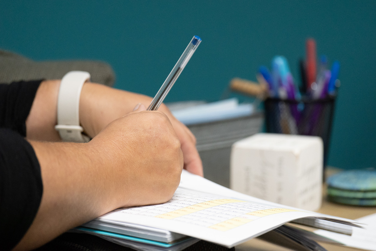 Person's hand poised over a ledger